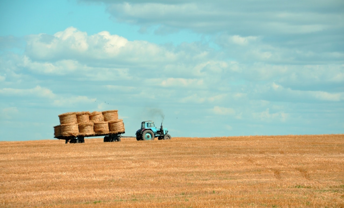a tractor pulls hay through a golden field